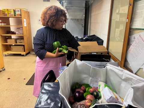  Rachel Niyonsaba, the project manager at the Dayton Equity Center, packing a bag of food at the McKinley church food pantry. 