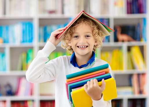 boy in classroom holding books.