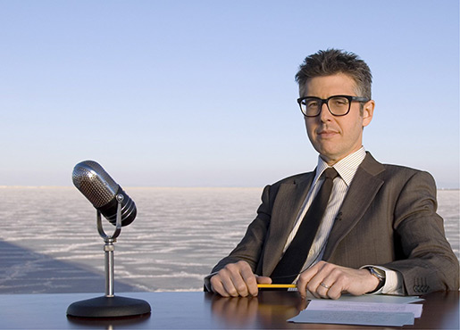 man sitting a desk with a microphone 