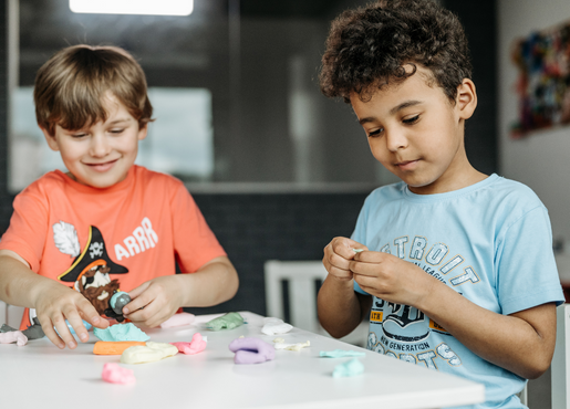 2 male children playing with play-do and paper 