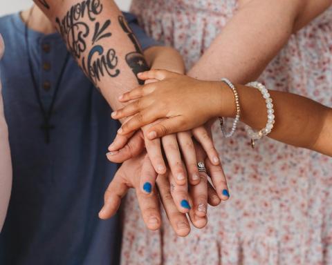 Samantha Stewart and her family pile their hands together for a family picture. She and her husband have fostered seven children, including a daughter with autism. 