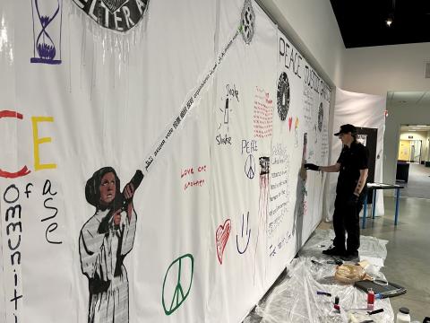 Yellow Springs artist Jonny No adds art to a wall of 'graffiti' at the Quaker Heritage Center at Wilmington College.