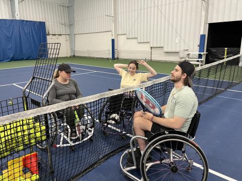 Logan Cover (center) chats with fellow adaptive athletes at a UC wheelchair tennis practice.