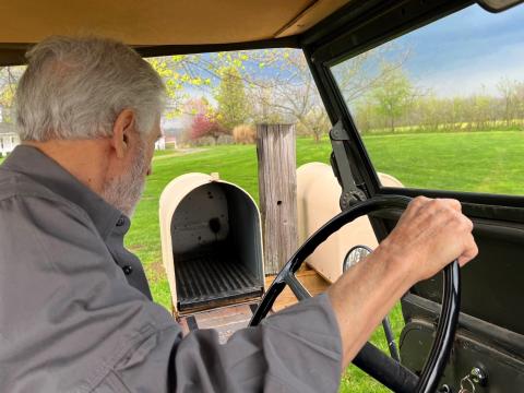 Chuck Klein checks his mail from the driver's seat of his ATV. His mailbox is located more than half a mile away from his home.