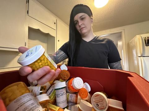 Casey Daulbaugh rummages through a bin of prescription medications inside her home in Bowling Green, Ohio.