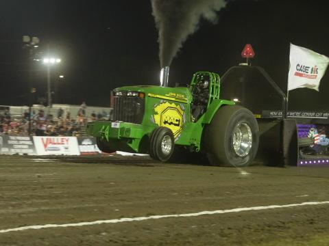 A John Deere tractor pulls a weighted sled at the National Tractor Pulling Championships in 2024.