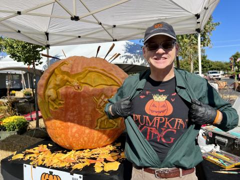 Gus Smithhisler, the 'Squashcarver,' poses in front of his latest pumpkin carving creation in Dublin.