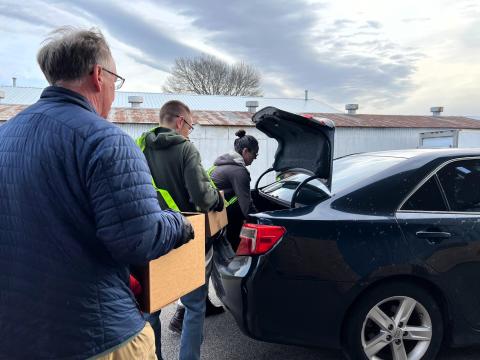Volunteers load boxes of shelf-stable food into a car. A DoorDash driver will then deliver the boxes to homebound seniors who live within a 10-mile radius.