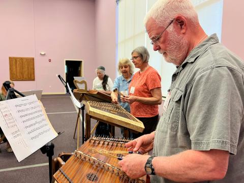 A group of students learn how to play the hammered dulcimer under the instruction of Chris Steiner at a church in Tipp City.