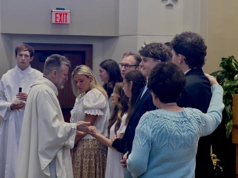 Fr. Robert Jones holds the hands of a student at the University of Dayton after anointing her for confirmation on Sunday, April 26, 2026.