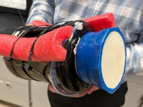 A scientist holds an early prototype of a buoy designed to slowly release algaecide into water.