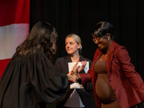 Faith Isaya (right) shakes hands with Judge Suzana Krstevski Koch (left) during her naturalization ceremony in the Brecksville-Broadview Heights High School auditorium.